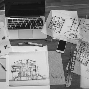 A set of building plans in front of a laptop.